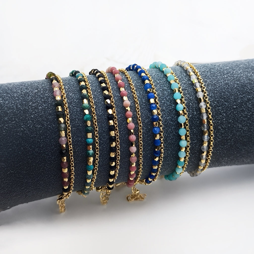 Assorted healing crystal gemstone bracelets displayed on velvet roll