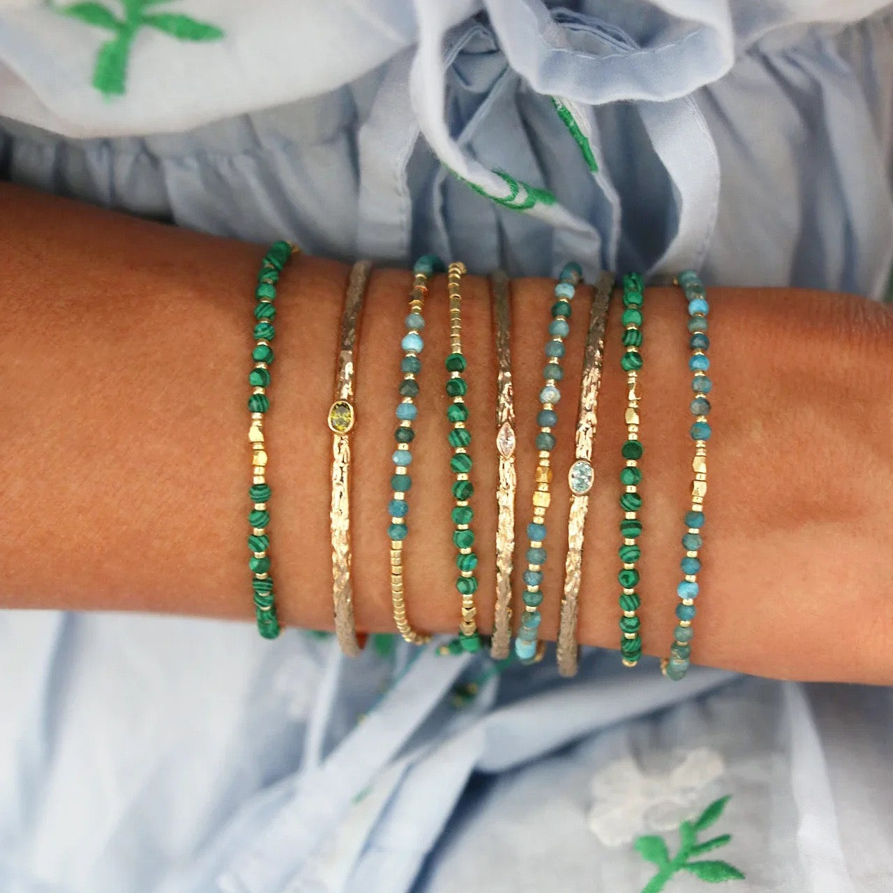 Gold wire beaded bracelets styled on wrist with multiple gemstones