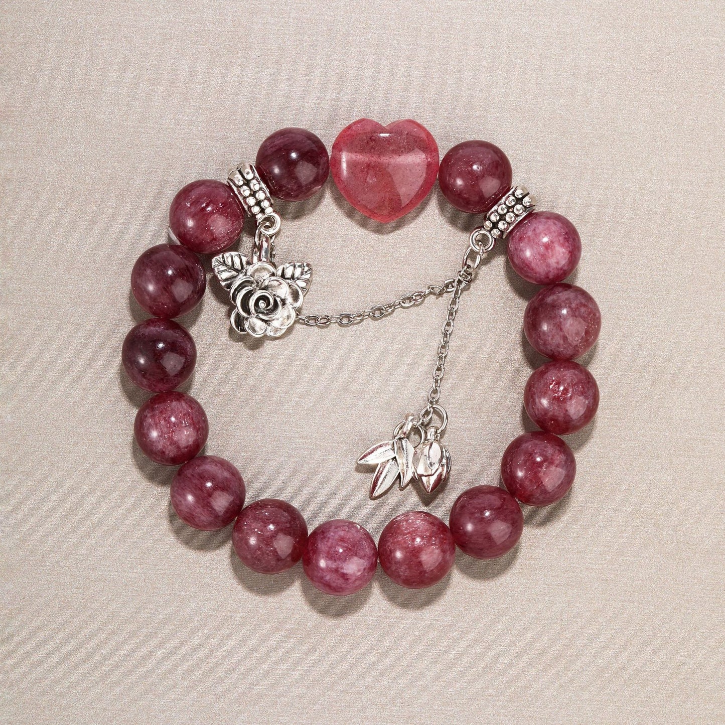 Side angle of strawberry quartz bracelet with soft lighting and silver leaf charms