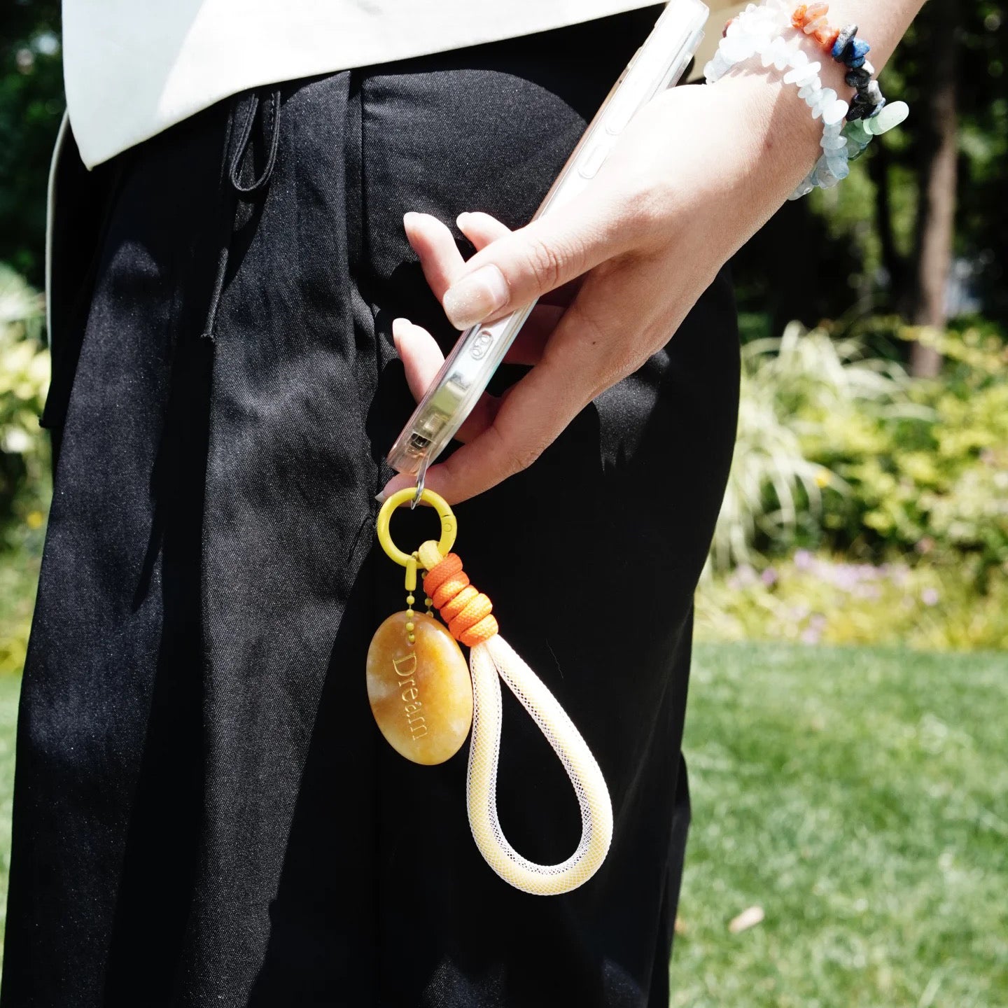 Woman holding phone with affirmation crystal charm hanging from case