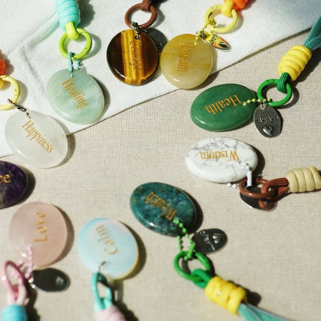 Flat lay of multiple affirmation keychains showing words and stones
