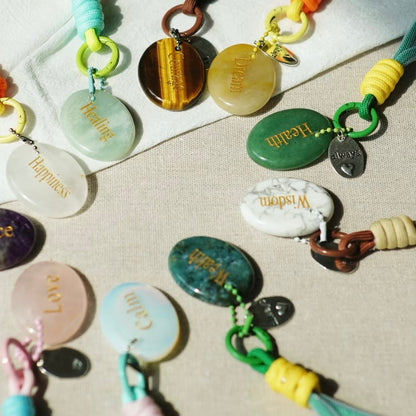 Flat lay of multiple affirmation keychains showing words and stones
