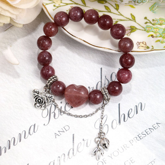Romantic styling of strawberry quartz bracelet on book with rose and leaf accents