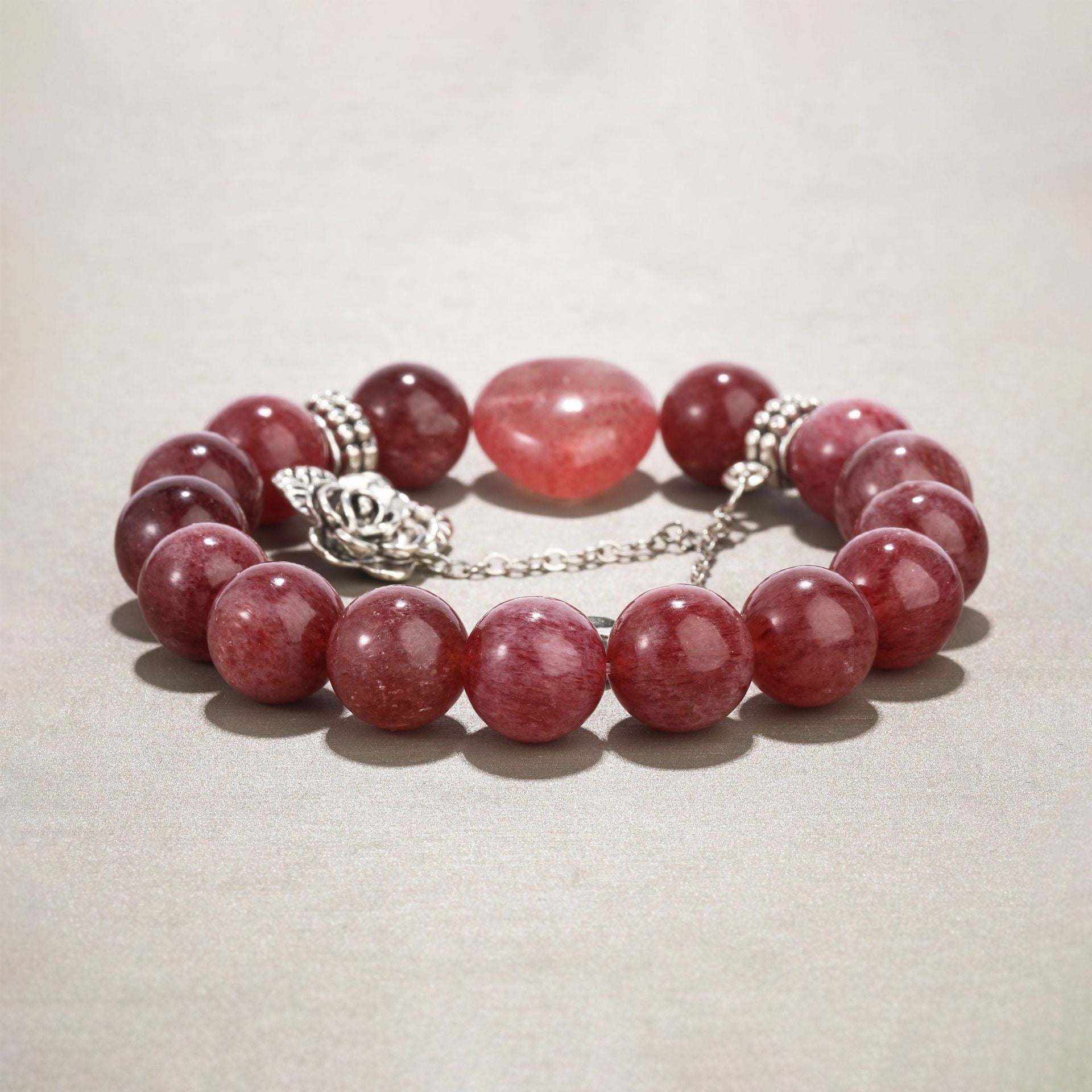 Flat lay of strawberry quartz bracelet showing heart gem and rose charm