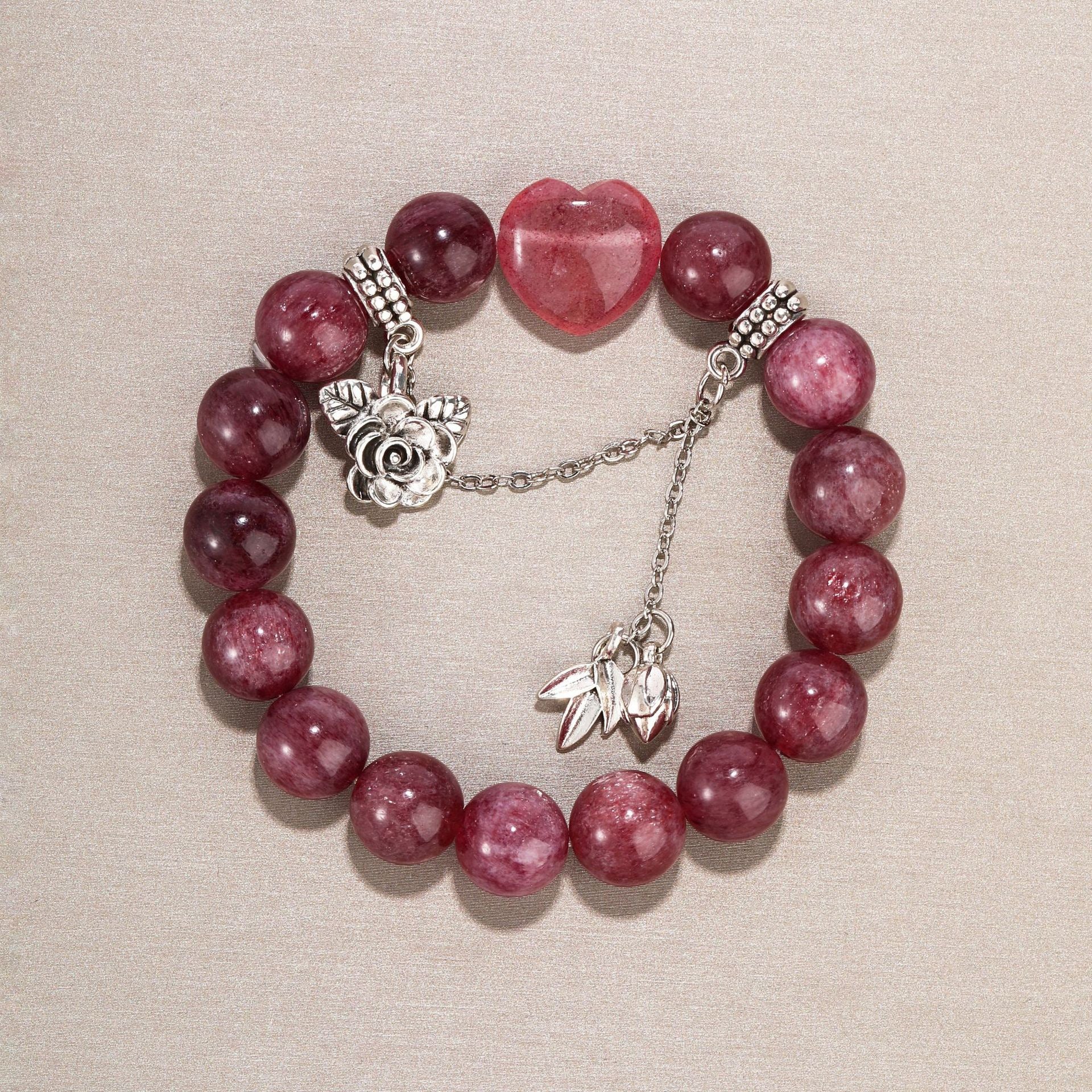 Side angle of strawberry quartz bracelet with soft lighting and silver leaf charms