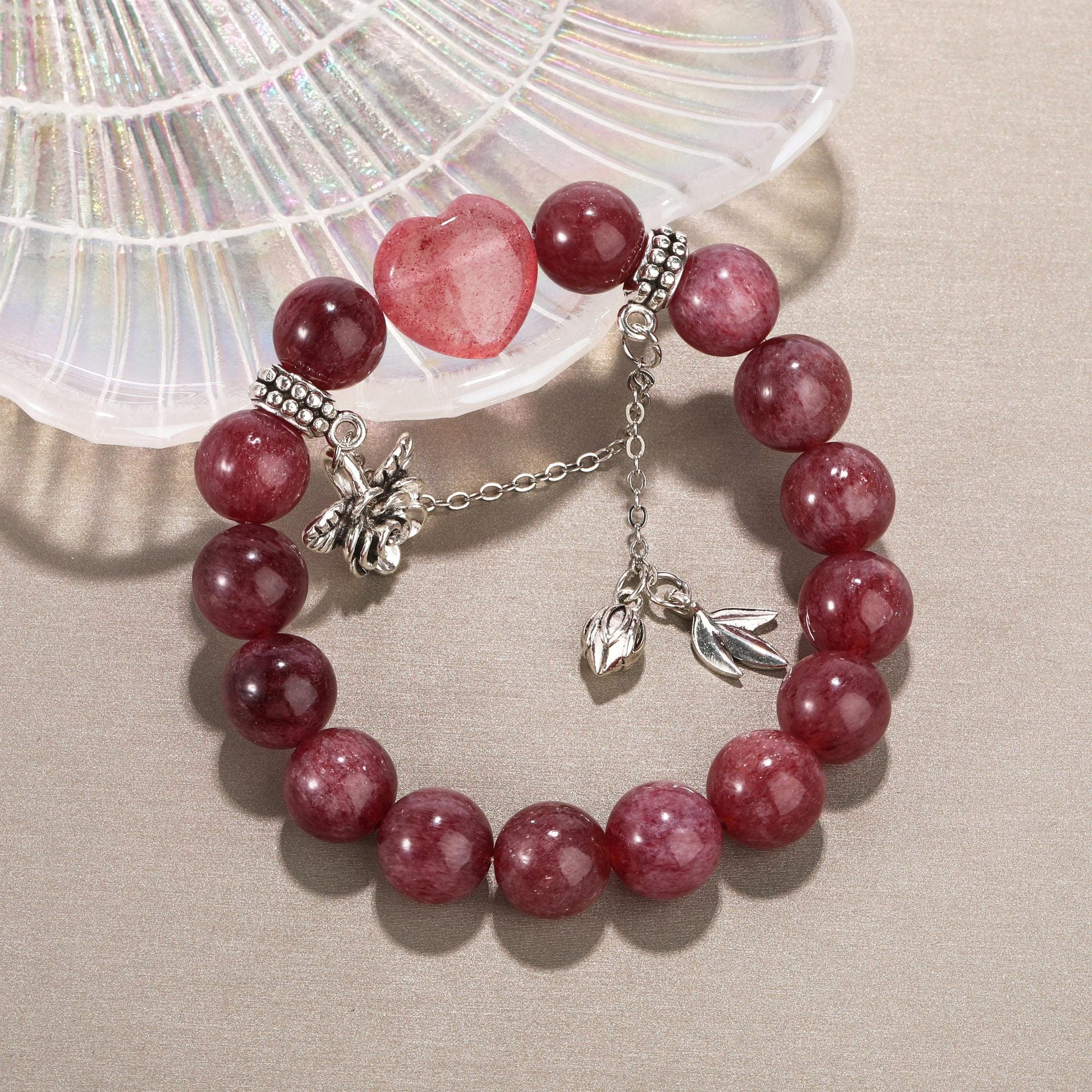 Strawberry quartz bracelet with heart-shaped stone displayed on shell background